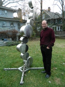 Barton Rubenstein poses next to one of his sculptures in his backyard. Photo by Suzanne Pollak