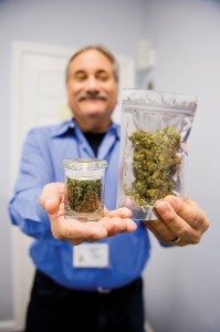 Rabbi Jeffrey Kahn, owner of the Takoma Wellness Center in Washington, D.C., holds up a sample bag of medical marijuana and a jar of trim, which can be used to cook marijuana-infused foods. Photo by David Stuck
