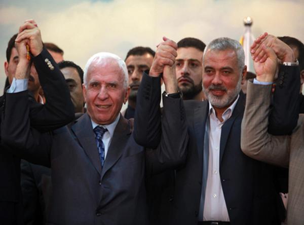 Head of the Hamas government Ismail Haniyeh (right) and senior Fatah official Azzam Al-Ahmed (left) raise their hands together at a news conference that announced a reconciliation agreement between the rival Palestinian factions in Gaza City on April 23. Photo by Abed Rahim Khatib/Flash90.