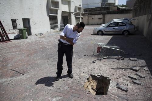 A man walks next to damaged shop that was hit by a rocket was hit by a rocket fired from the Gaza strip in Ashdod, on the second day of Operation Protective Edge, July 9, 2014. Photo by Yonatan Sindel/Flash90 