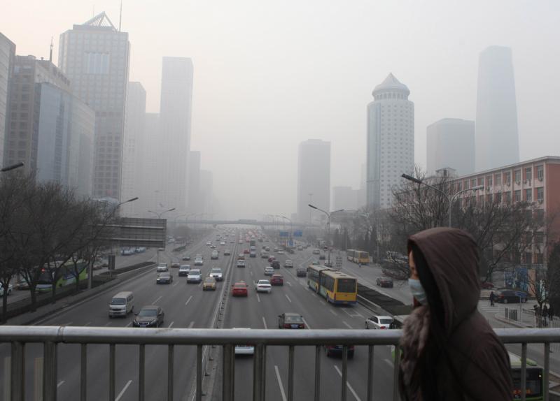 A woman on a pedestrian walk in Beijing covers her mouth with a mask to protect against the smog. Flickr photo