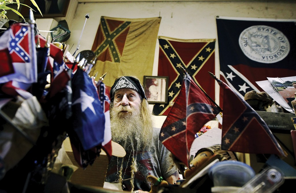 Dent “Wildman” Myers, surrounded by Confederate battle flags, talks to customers in his Civil War surplus store in Kennesaw, Ga. Myers says he has been busy nonstop selling Confederate flags and has received calls from across the country since the flag was banned by retailers Walmart and Amazon.  Newscom