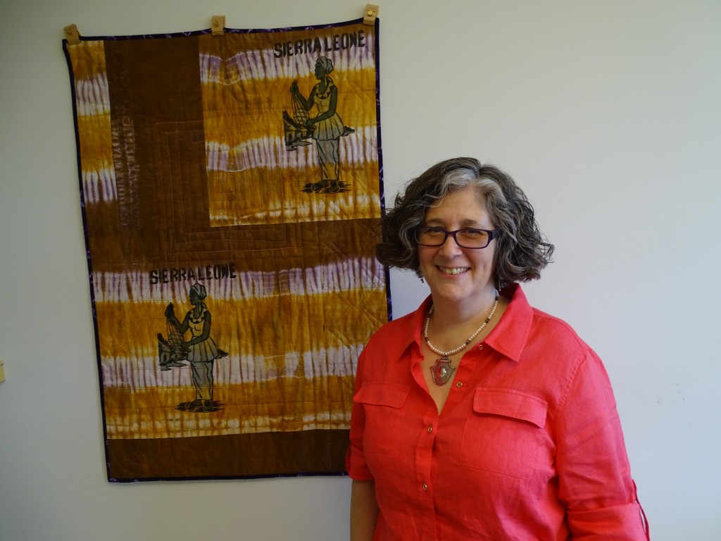 Martha Saldinger stands by a wall hanging in her Crystal City office that was made from material she bought in Sierra Leone. Photo by Suzanne Pollak