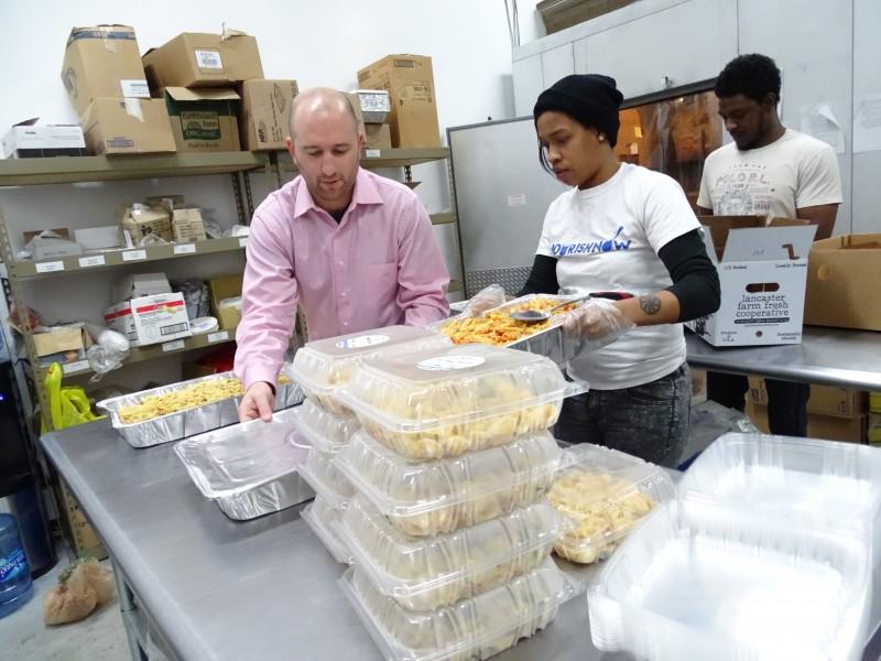 Brett Meyers, founder of Nourish Now, helps package hot meals. Photo by Suzanne Pollak