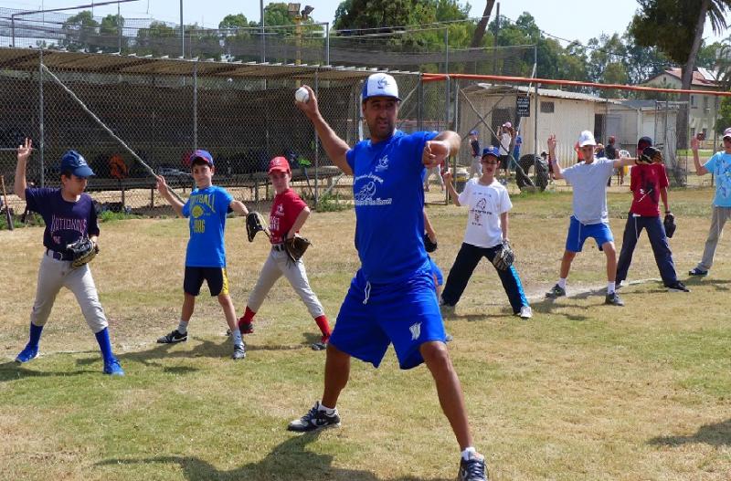 Nate Fish, director of the Israel Association of Baseball, demonstrates pitching to Israeli children.Photo Margo Sugarman/IAB via JTA