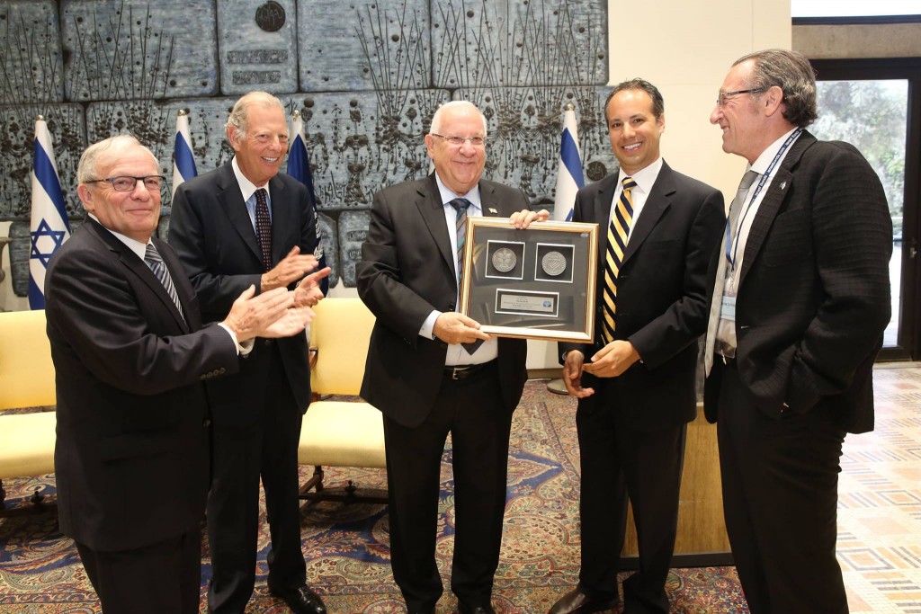 Israel Bonds President and CEO Izzy Tapoohi and Board Chairman Richard Hirsch applaud as Israeli President Reuven Rivlin is presented with the commemorative Bonds 65th anniversary medal by board member Jason Schwartz and international board member Jaime Schmidt Neuman Photo by Yossi Zamir.