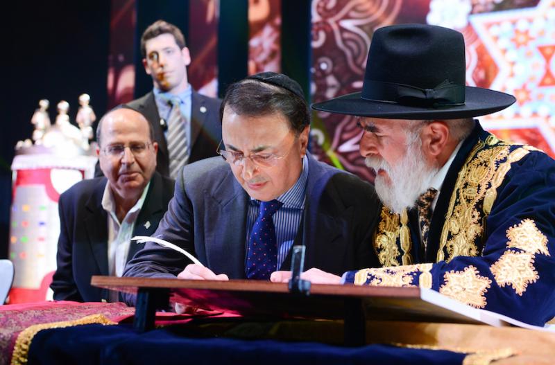 Lev Leviev, center, writes in a Torah scroll with Rabbi Eliyahu Yaakov, right, and Israel’s then-defense minister, Moshe Ya’alon, in Jerusalem in 2014. Photo by Israel Barddougo/ World Congress of Bukhara Jews via JTA