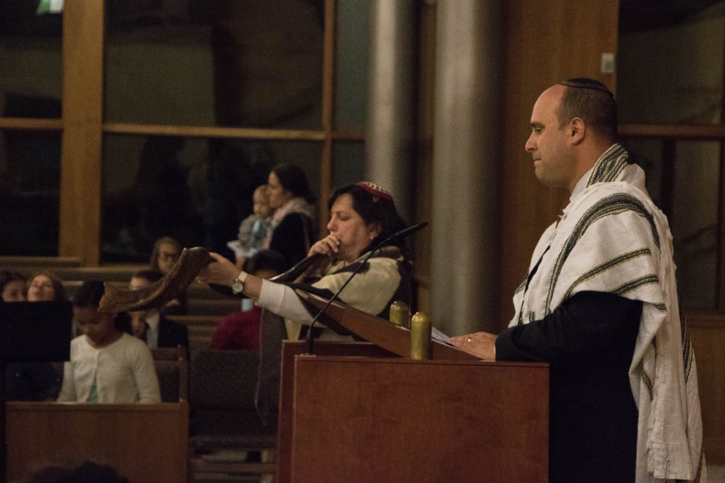 Rabbi JanetOzur Bass begins the service by blowing the shofar as Rabbi Adam Raskin listens.