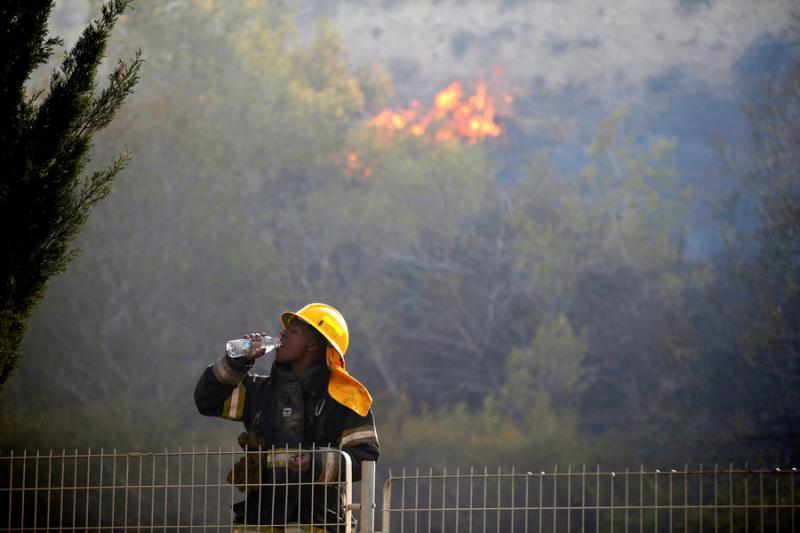 A firefighter drinks water as a wildfire burns in the northern city of Haifa, Israel, on Nov. 24. REUTERS/Baz Ratner. Photo via Newscom.
