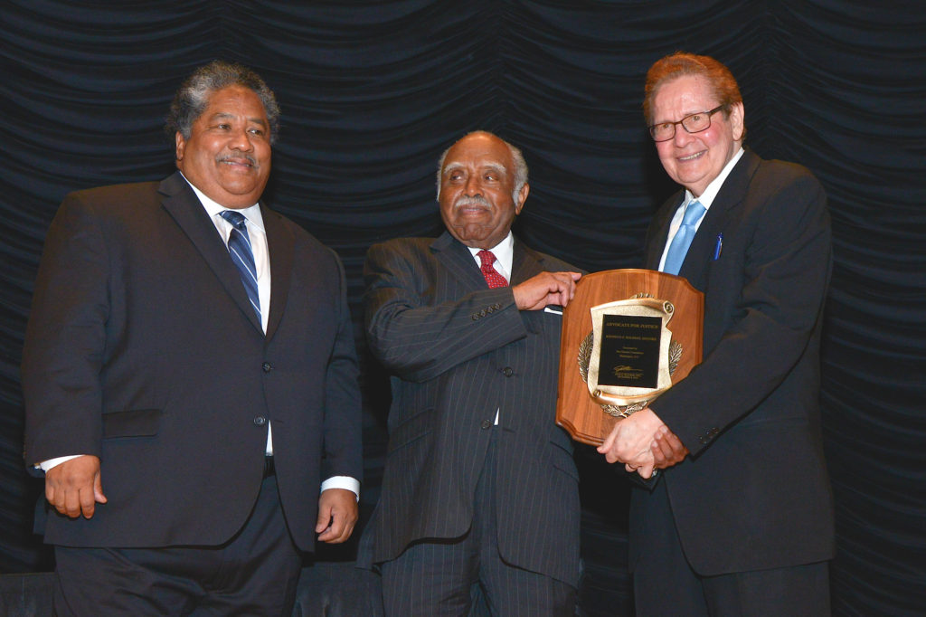 Attorney Josh Olender, right, presents the 31st annual Olender Foundation Advocate for Justice Award to Kenneth Holbert, center, as Judge Alex Manuel watches. The ceremony took place on Dec. 8 at the Ronald Reagan International Trade Center. Photo by Marshall Cohen 