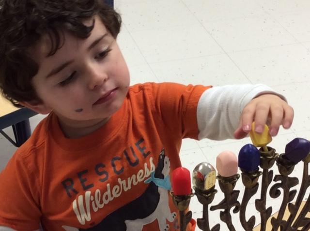 A member of the 2-year-old class at Greenzaid Early Childhood Center at Congregation B’nai Tzedek in Potomac explores Chanukah objects. Photo by Kathy Goldstein 