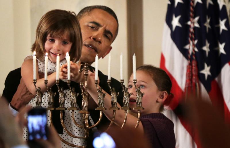 President Barack Obama holds up Kylie Schmitter, 4, to light a menorah as Kylie's sister Lainey looks on during a 2013 Chanukah  reception at the White House. Photo by Alex Wong/Getty Images